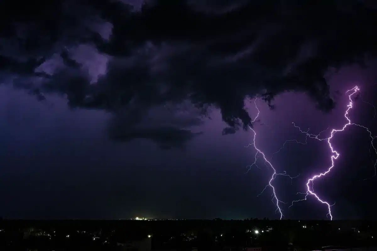 Storm clouds gathering over an airport tarmac, lightning illuminating the sky, aircraft grounded at gates, dramatic dark sky