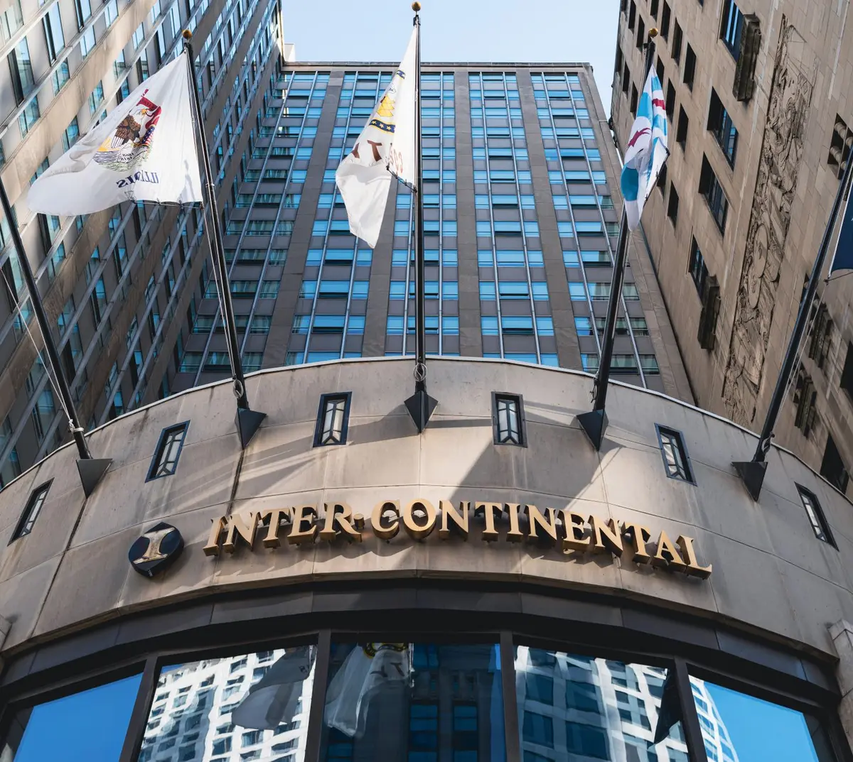 A formal entrance to a luxury hotel with security personnel stationed discreetly, metal detectors and screening checkpoints visible but orderly, professional security presence evident, evening lighting, no crowds or identifiable individuals.