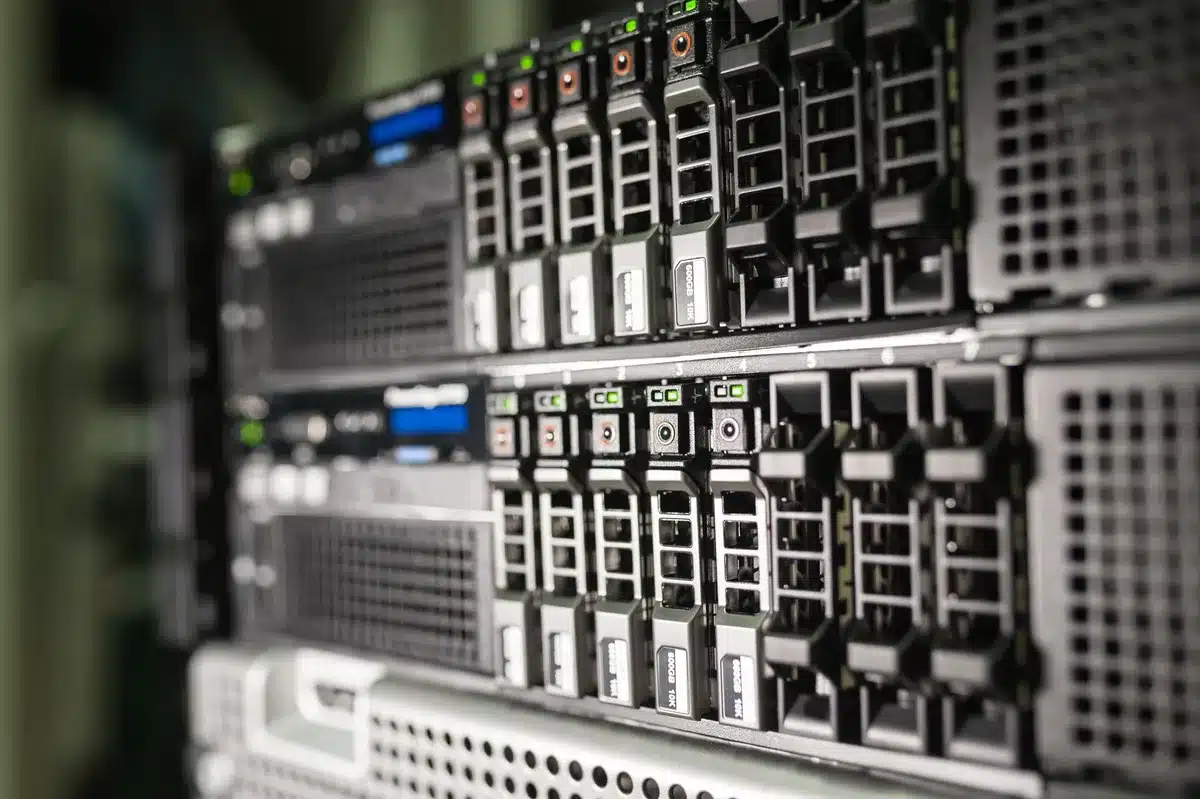 An expansive data center facility floor with rows of server racks and glowing blue indicator lights, cables neatly organized overhead, the scale of infrastructure visible in the depth of the image, a sense of massive computational power.