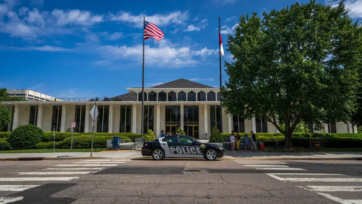 A federal courthouse entrance with steps and columns, overcast light, papers scattered on a desk nearby, tension and legal weight