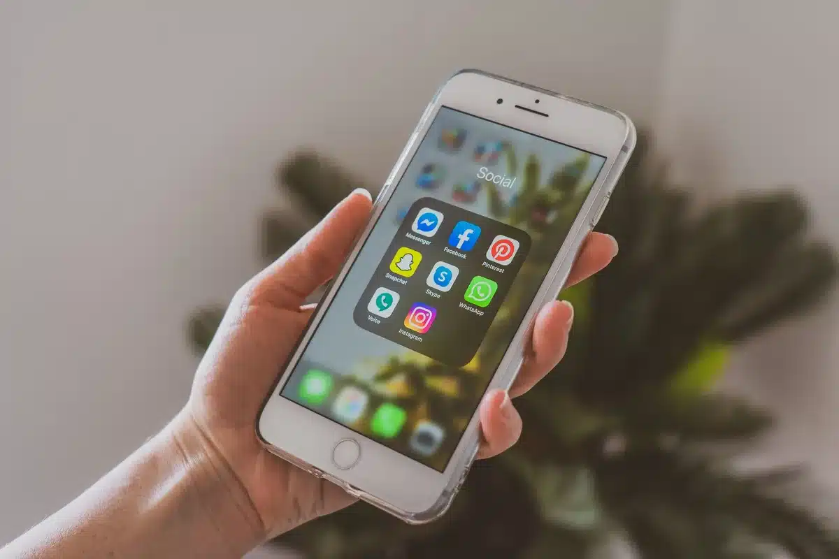 A Truth Social post glowing on a smartphone screen in dim light, the text blurred but the notification icon visible, a hand holding the device