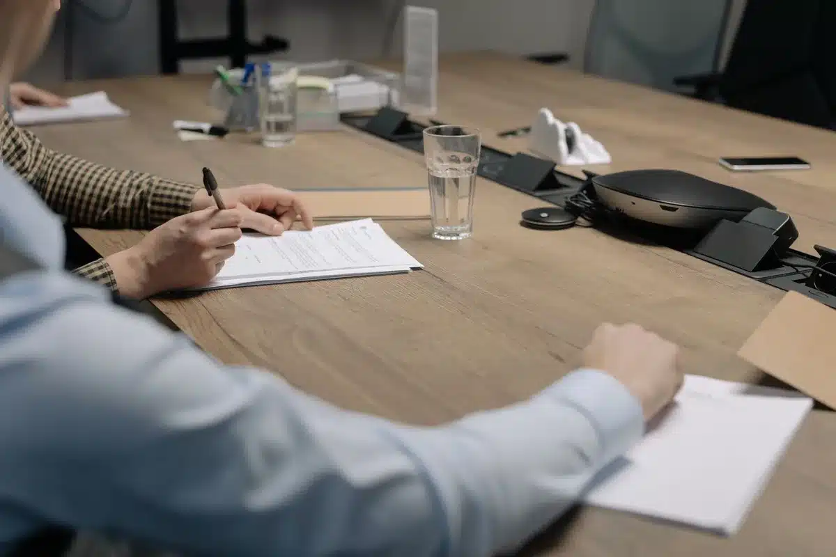 Two airline logos side by side on a boardroom table with financial documents and a gavel, suggesting corporate negotiation and antitrust considerations