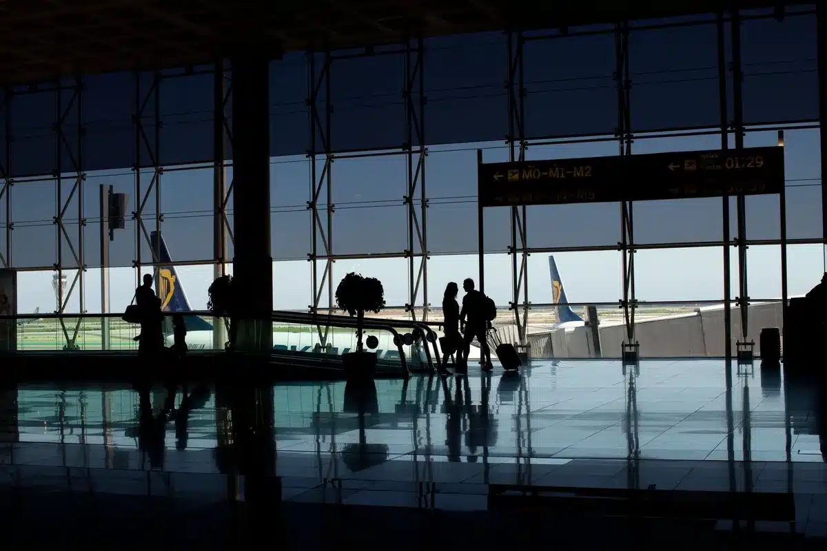 Empty airport terminal gate with departure boards showing multiple destinations, symbolizing the scale and complexity of major airline operations