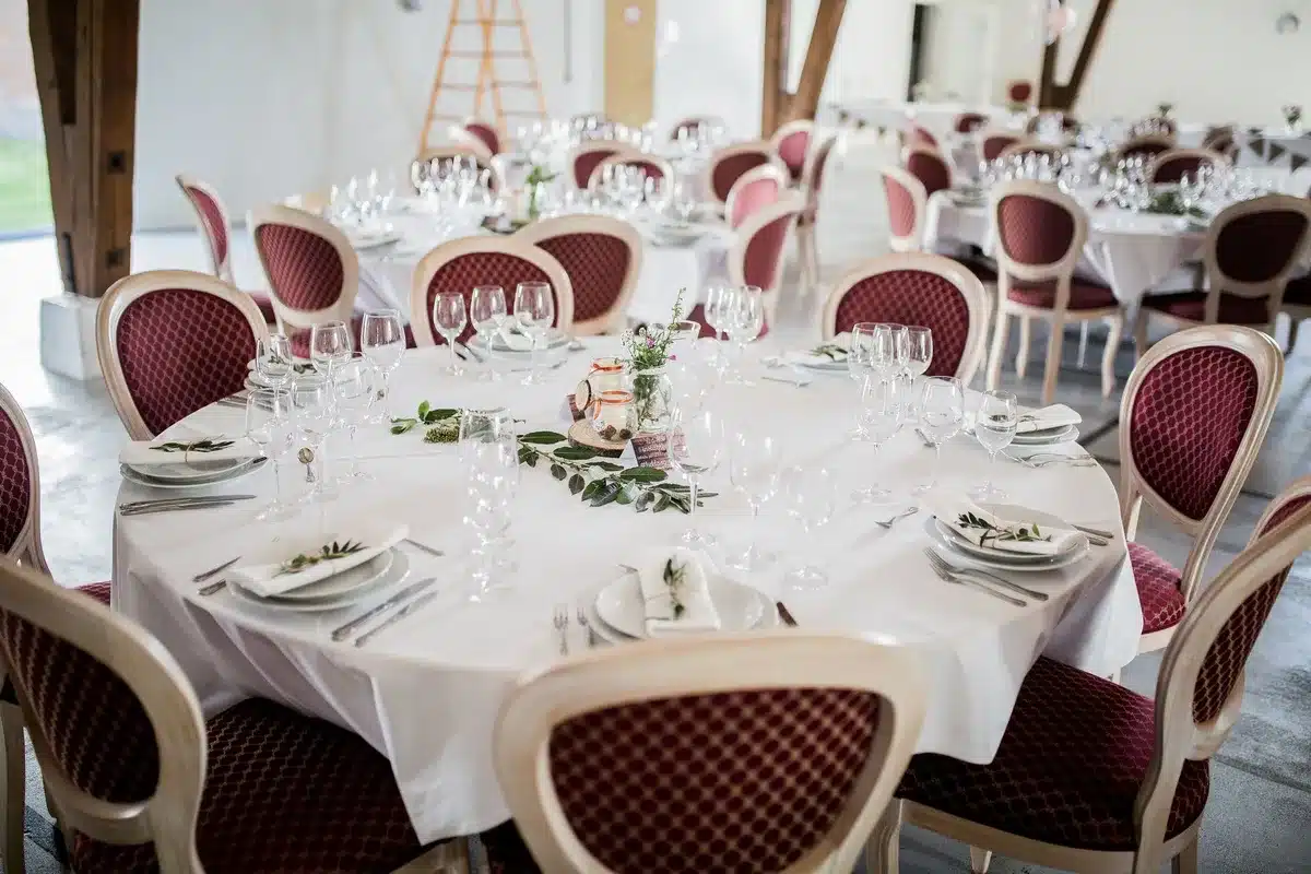 A formal banquet hall setting with empty tables, place settings, and podium under soft lighting, ready for an evening event.
