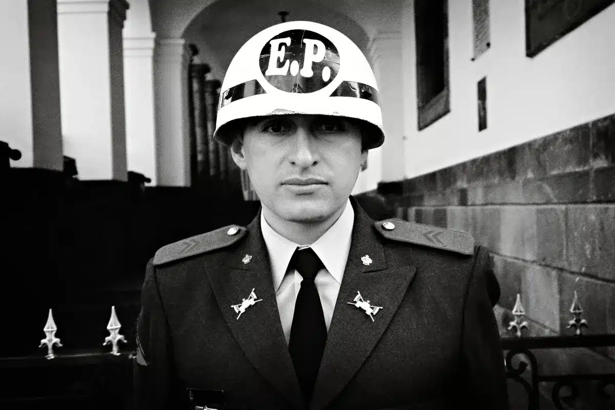 A Secret Service officer in formal attire standing alert in a secure venue corridor, professional and composed.