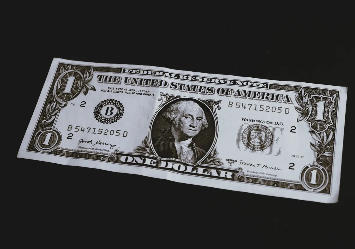 A close-up of a 30-year Treasury bond certificate or document with numbers and official seals visible, slightly out of focus in background