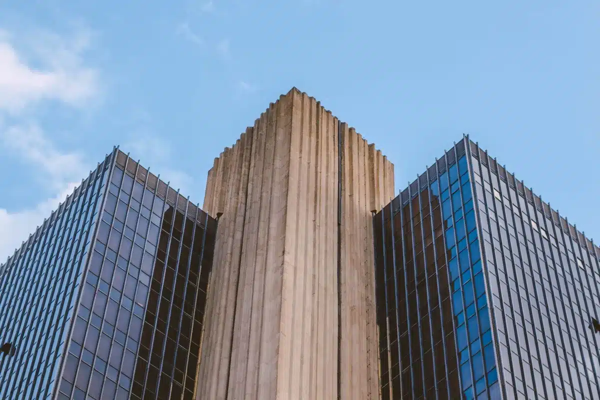 A federal appeals court building's imposing stone facade with columns and steps, American flags flanking the entrance, bright morning light casting sharp shadows across the marble plaza, conveying institutional authority and judicial finality.