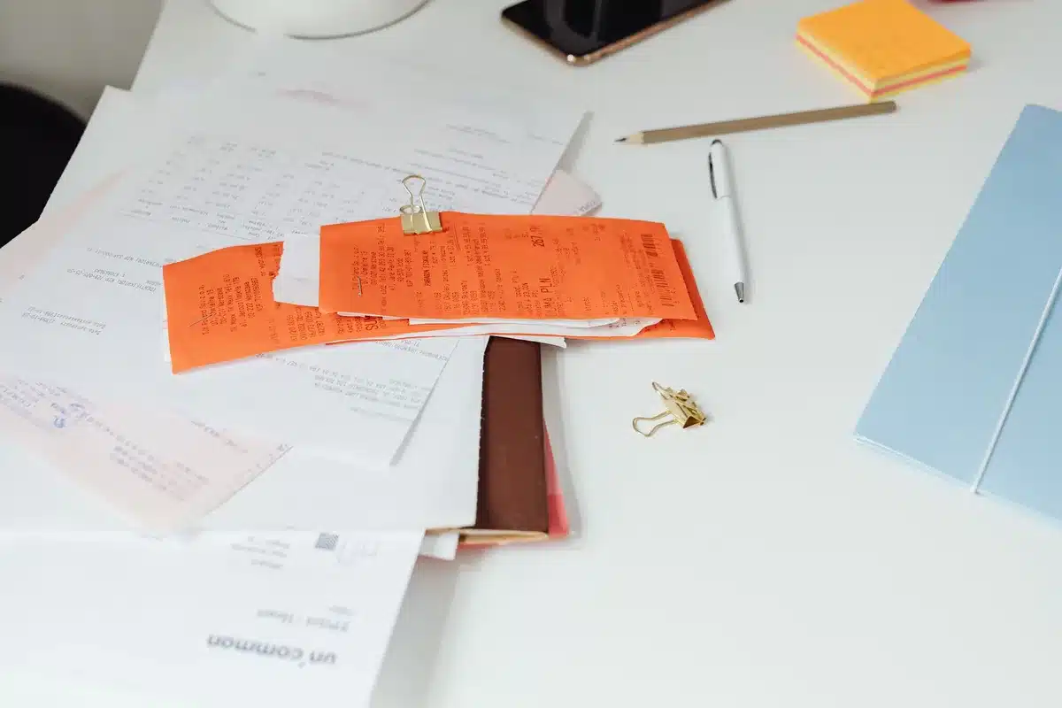 Stacks of student loan documents and statements scattered on a desk, with a calculator and pen visible, representing the financial burden of college debt