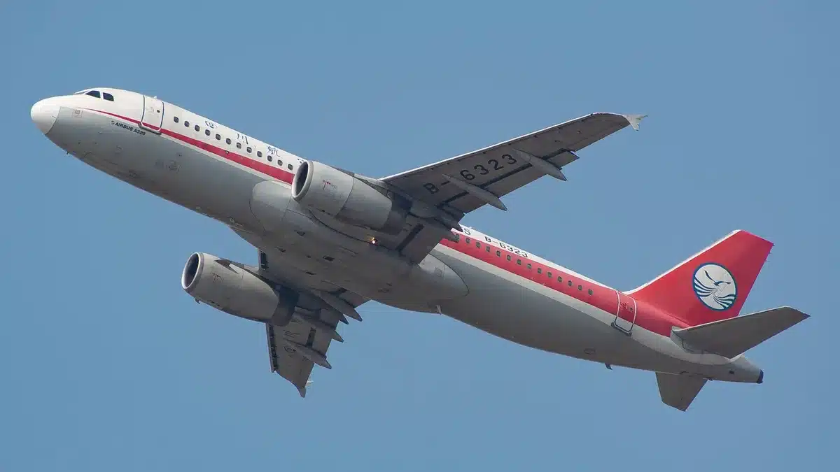 A commercial aircraft in flight against a blue sky, viewed from below, showing the wing and fuselage structure in normal operation