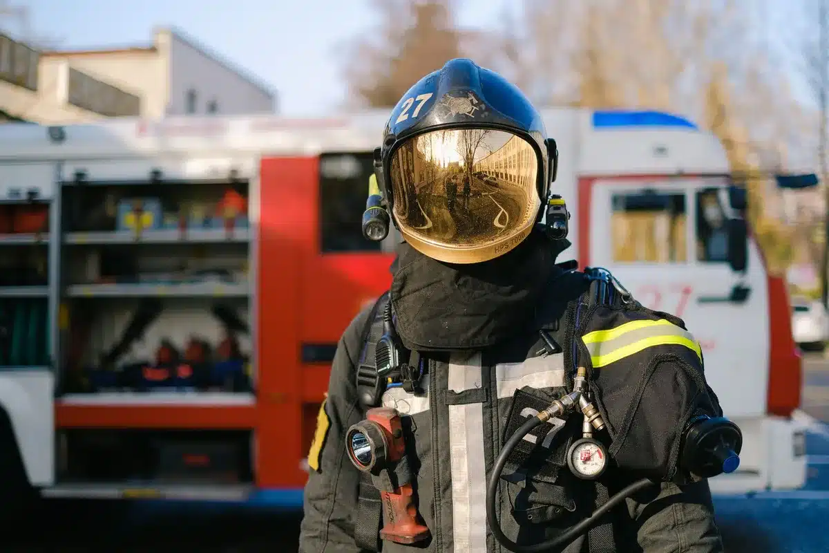Campaign event with firefighters in uniform listening to a Democratic candidate speak at a podium, flags and union banners visible in the background