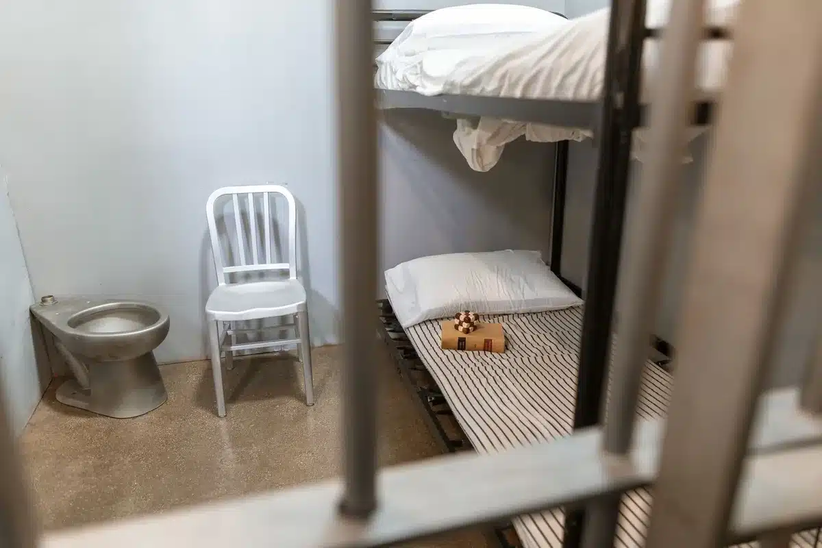 Military detention facility interior with secure corridor, institutional lighting and metal fixtures, sparse and austere environment conveying lawful restraint.