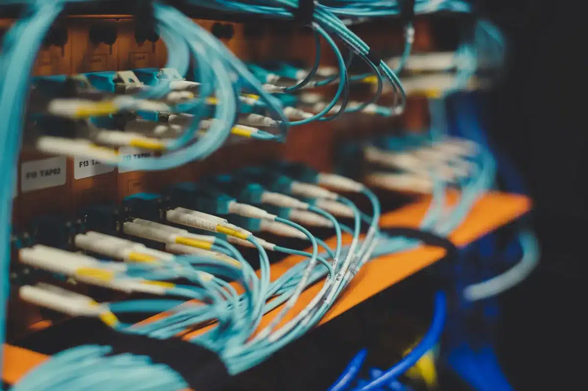 A semiconductor server rack in a data center with blue and green indicator lights glowing, rows of equipment stacked vertically, cables running between units, emphasizing scale and connectivity