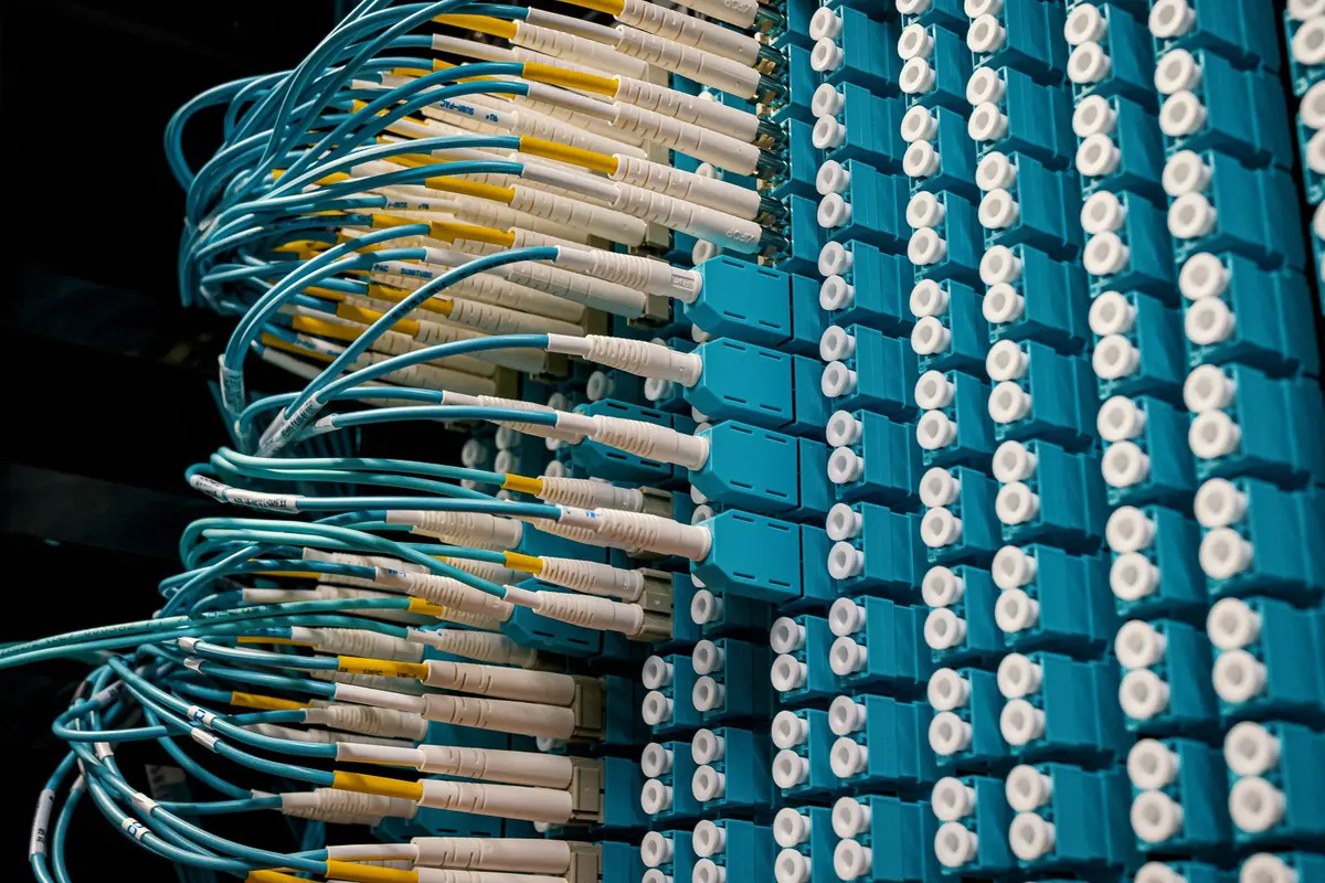 A glowing server rack in a data center, blue and green lights illuminating circuit board pathways, cables neatly bundled, representing massive computational infrastructure.