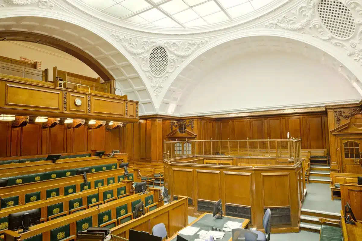 A marble-columned courthouse interior with empty benches and soft natural light streaming through tall windows