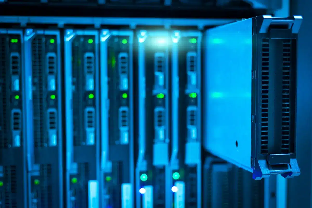 A glowing server rack with blue and white LED lights, rows of equipment stretching into the distance, indicating massive data center infrastructure and computing power