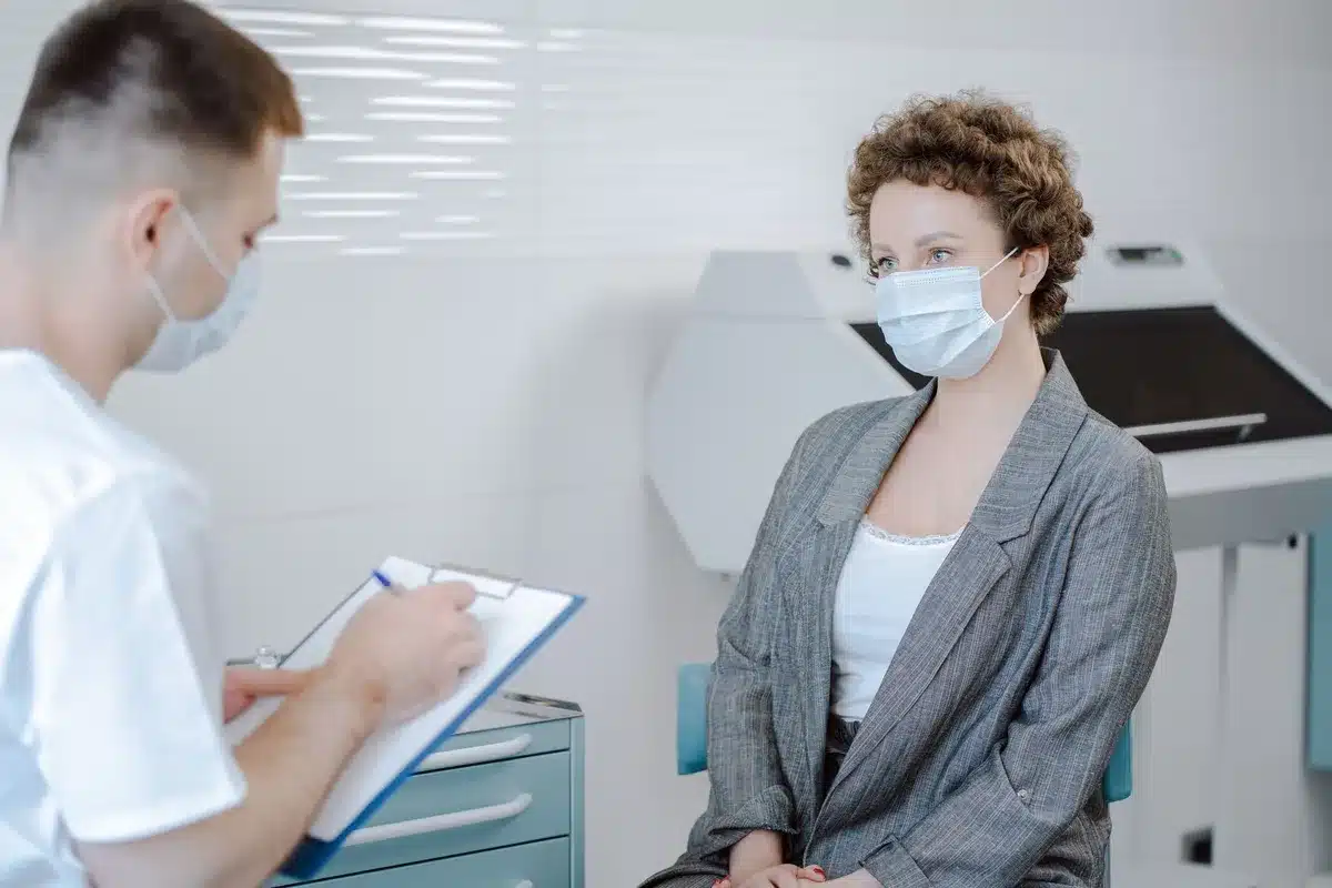 A medical consultation room with fertility charts and diagrams on the wall, a comfortable chair facing a desk with a computer screen, soft natural light from a window, conveying a professional yet supportive healthcare environment.