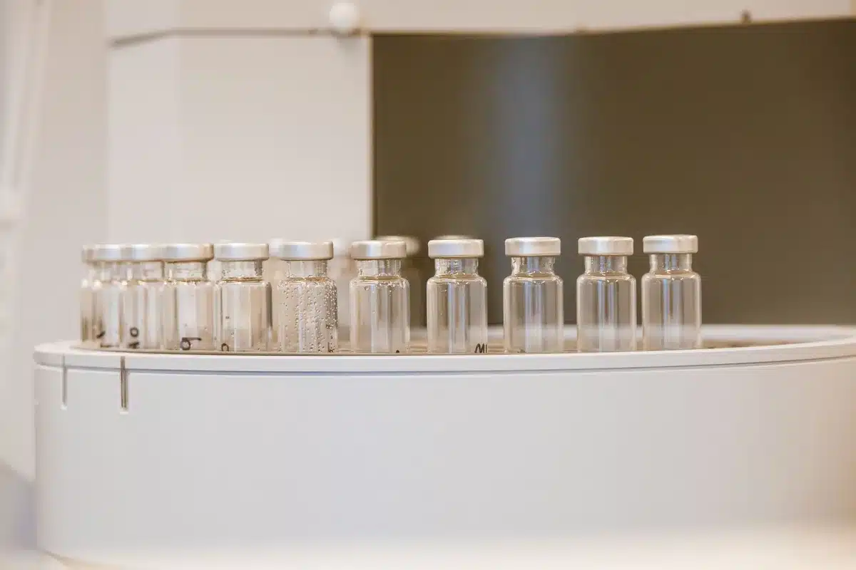 A medical vial with clear liquid under clinical lighting, set against a soft-focus medical environment, symbolizing fertility treatment and personal choice.