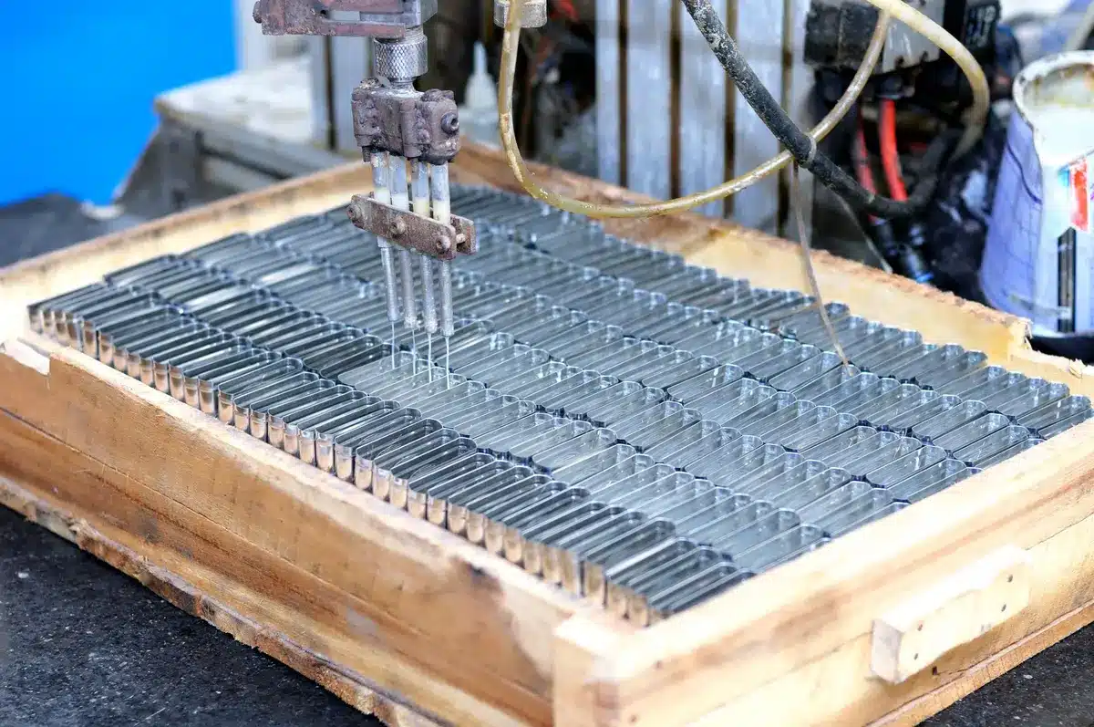 A manufacturing facility assembly line with unfinished satellite components on workstations, technicians in protective gear inspecting hardware, metal frames and solar panels visible