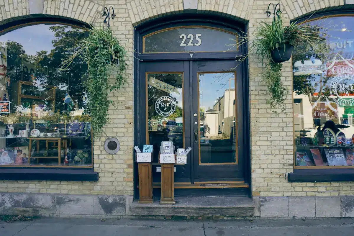 A distinctive three-story brick storefront with large display windows on a historic downtown street, morning light casting long shadows, a closed sign visible on the door, the building standing quiet and empty