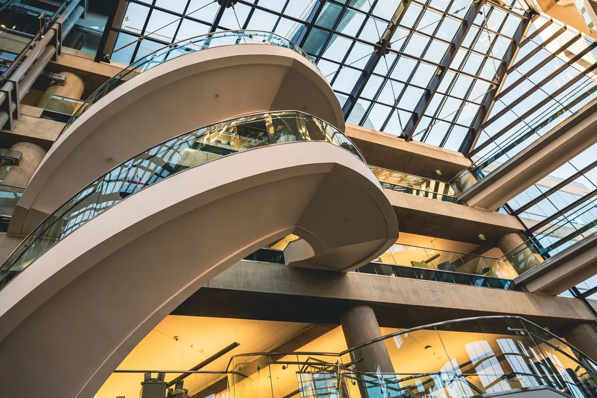 Modern office building interior with glass conference room and financial data displays on screens