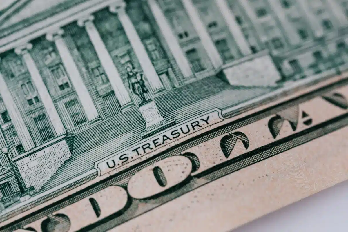 A Treasury Department press release document on a desk with financial charts and rising yield graphs visible in the background, representing the policy intervention.