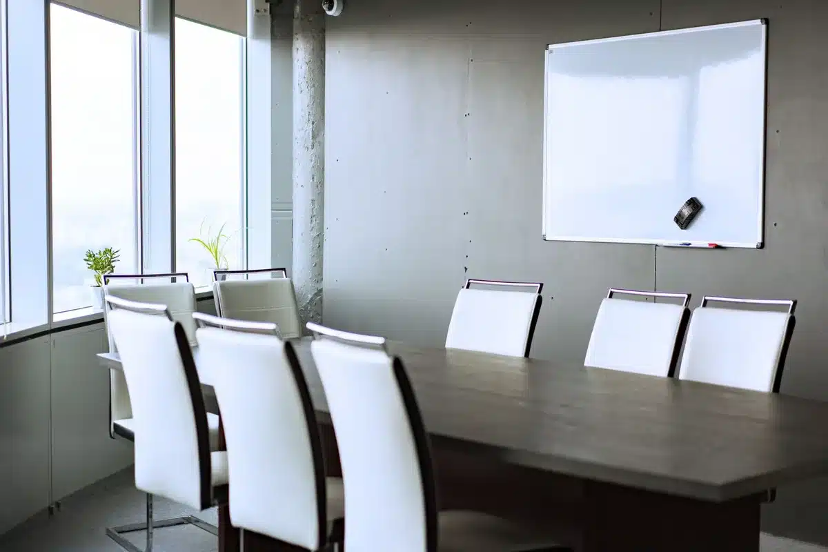 Gleaming modern stadium interior with executive boardroom overlooking the pitch, neutral tones and glass surfaces, no people visible, investment and governance theme