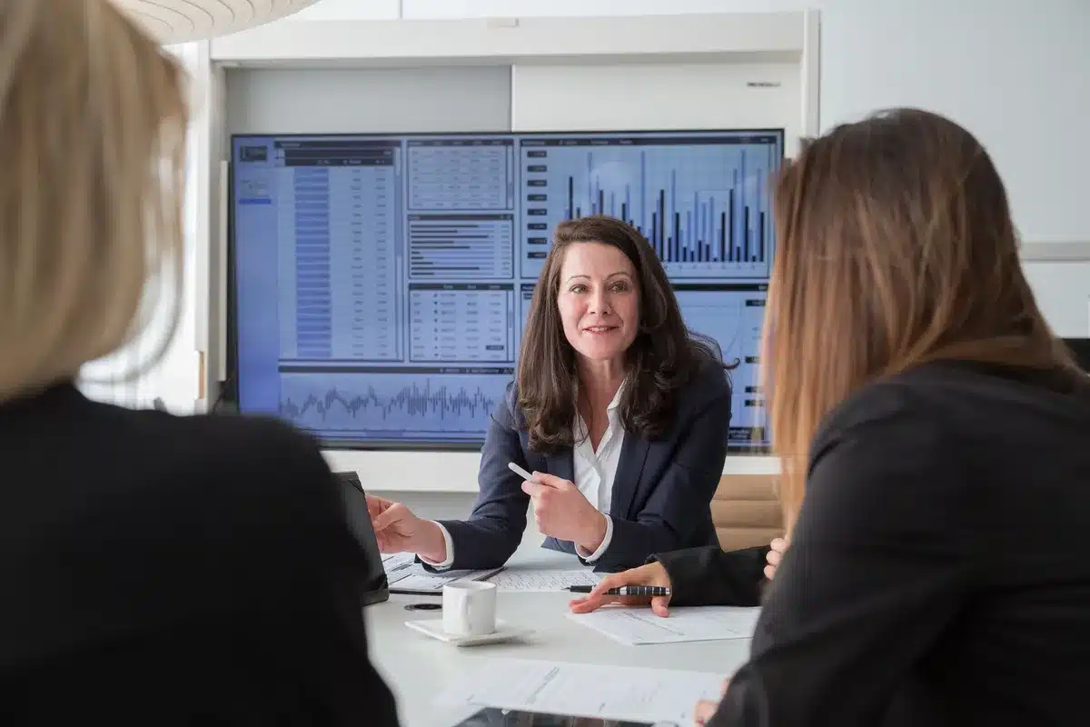 Luxury boardroom interior with mahogany table and leather chairs, soft lighting on financial documents and digital screens displaying stock markets and investment portfolios