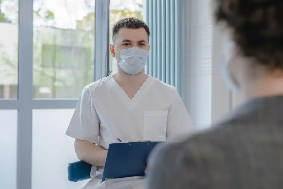 A somber medical consultation room with an empty chair and soft lighting, documents on a desk, suggesting serious health matters and difficult conversations