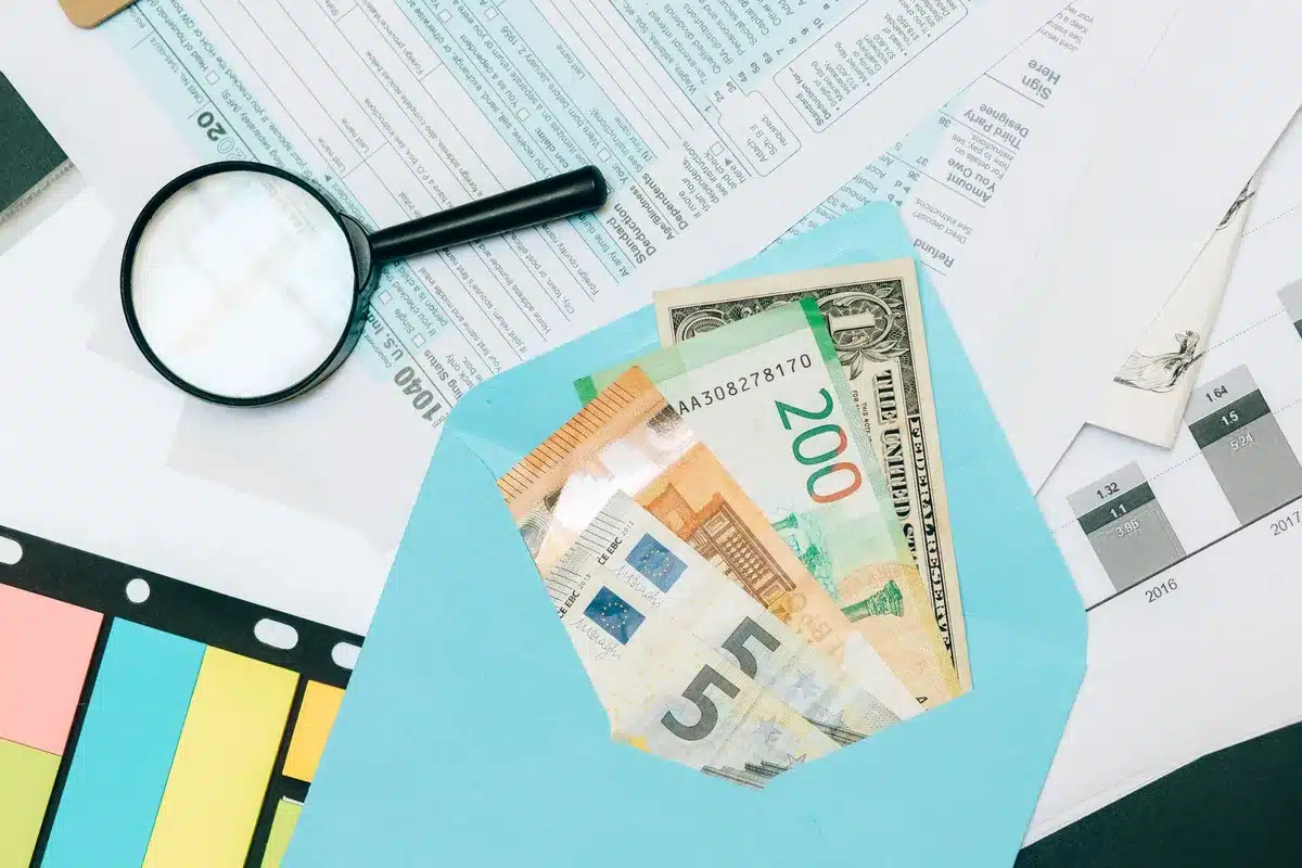 A close-up of hands signing a document or opening an investment account on a tablet, with a calculator and financial planning materials visible on a wooden desk, representing the enrollment process.