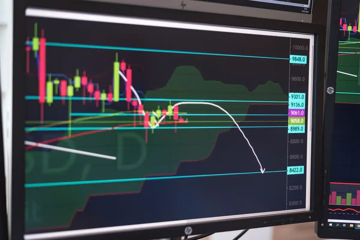 A dimly lit cryptocurrency trading terminal displaying Bitcoin's price chart with red candlesticks trending downward, a glowing ticker showing $63,000, and blurred market data in the background.