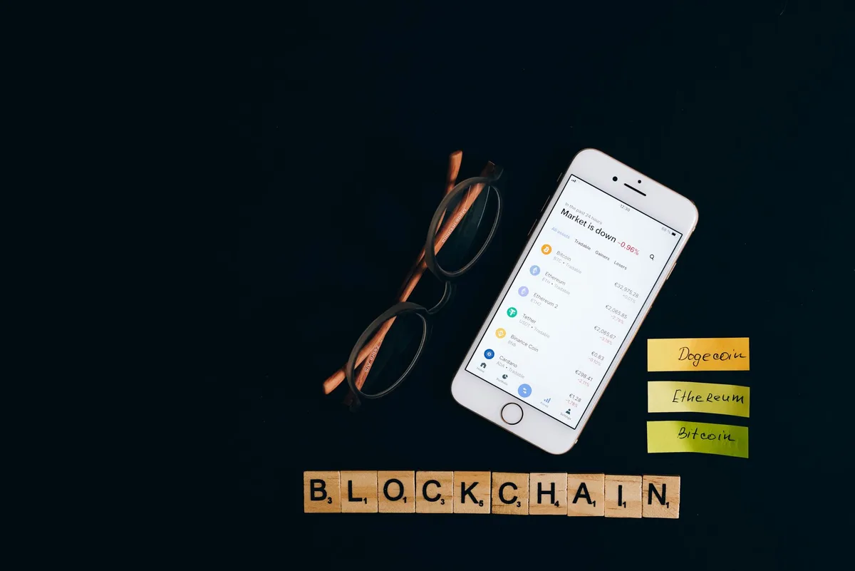 An anonymous hand holding a smartphone displaying a Bitcoin wallet with rising price notifications, screen glow illuminating the fingers against a dark background