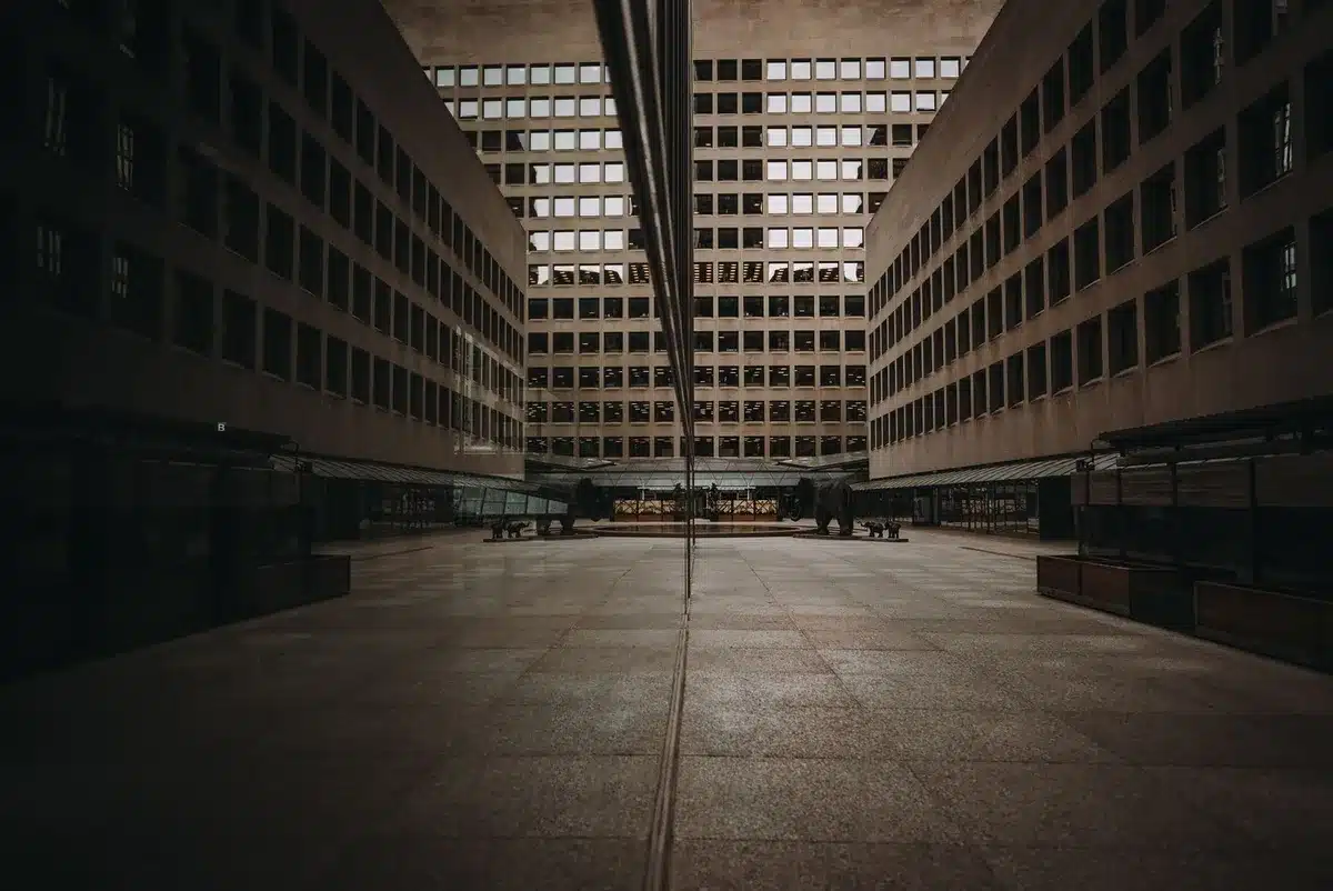 A modern government building interior with marble columns and an American flag, subtle glow of digital data streams in the background, conveying institutional authority and financial policy-making.