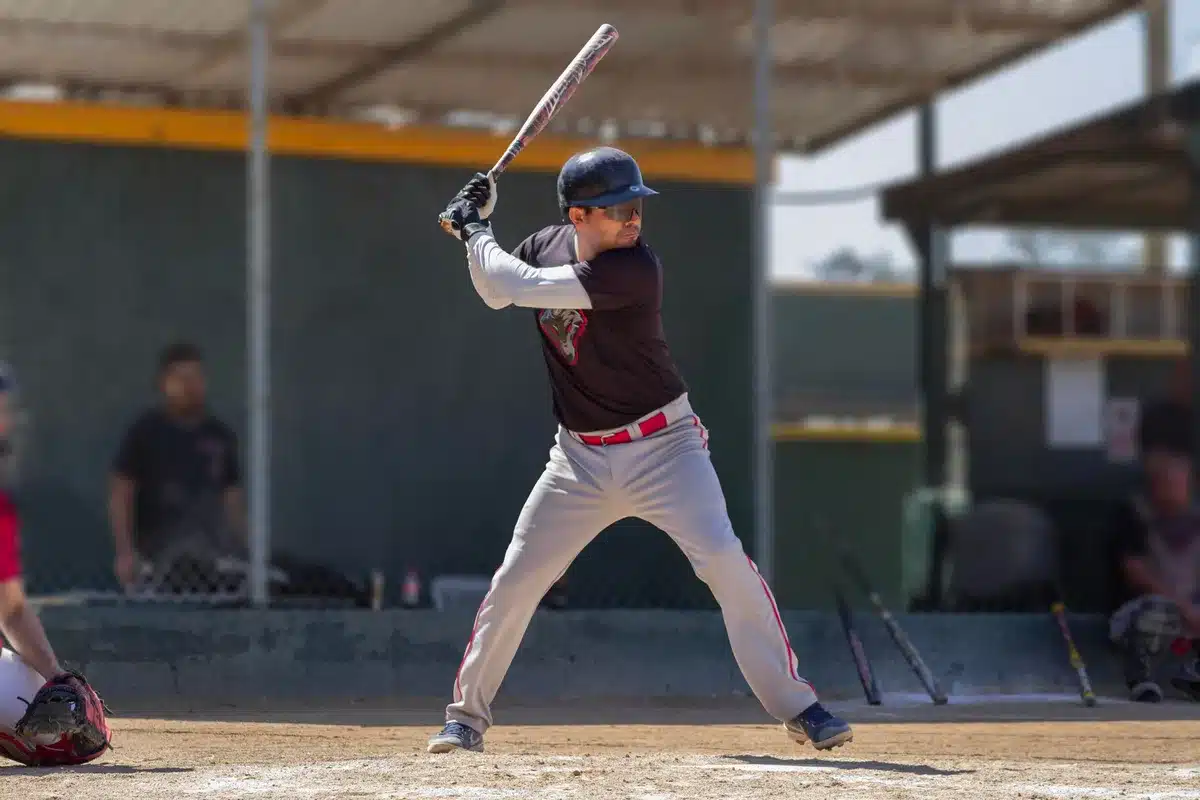A baseball player at bat in a stadium setting, two doubles already recorded, focused intensity on the batter's face, sunlit infield grass, anticipation and momentum captured mid-swing