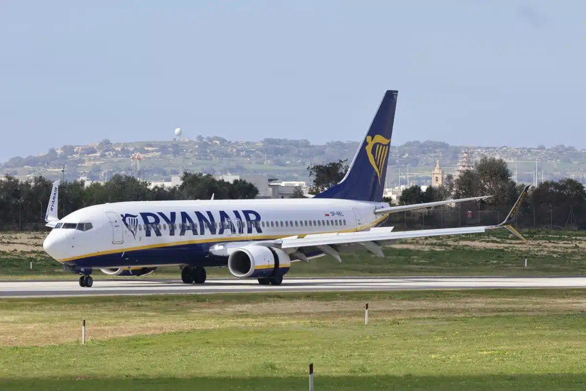 A modern single-aisle jetliner on a bright tarmac at dawn, fuselage gleaming white, engines and winglets sharp against clear sky, ground crew figures distant, suggesting readiness for first flight