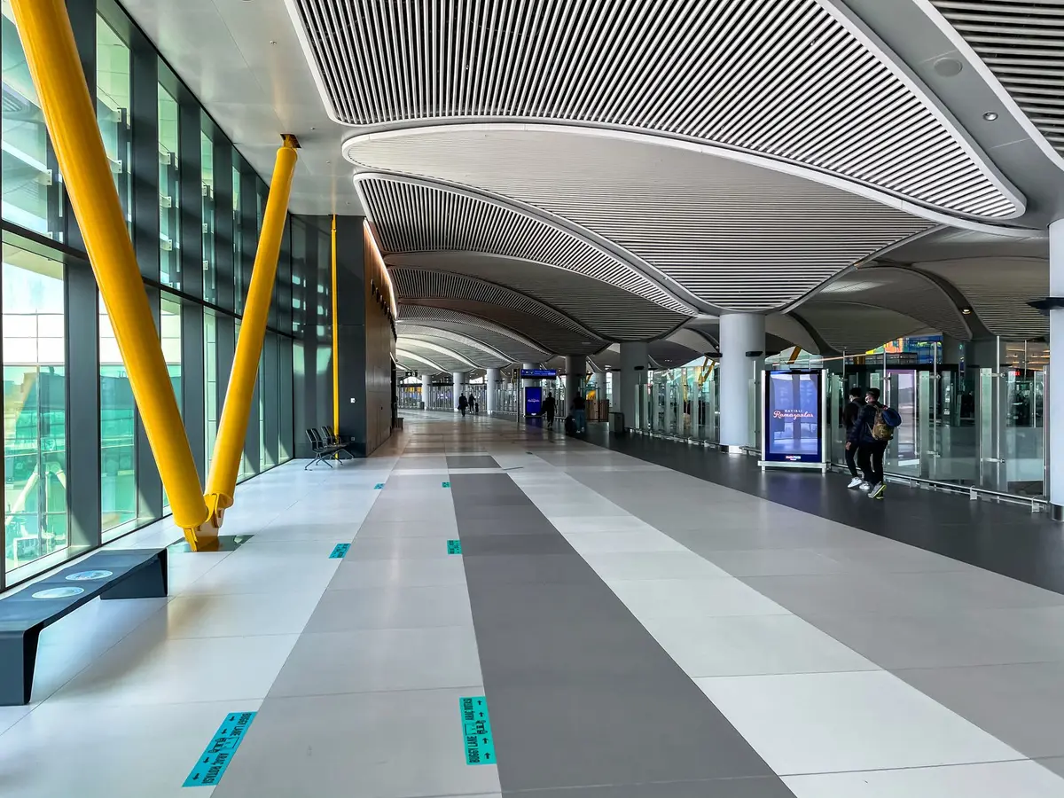 Airport terminal interior with modern seating, natural light from skylights, travelers waiting, contemporary architecture with clean lines, contemporary design aesthetic