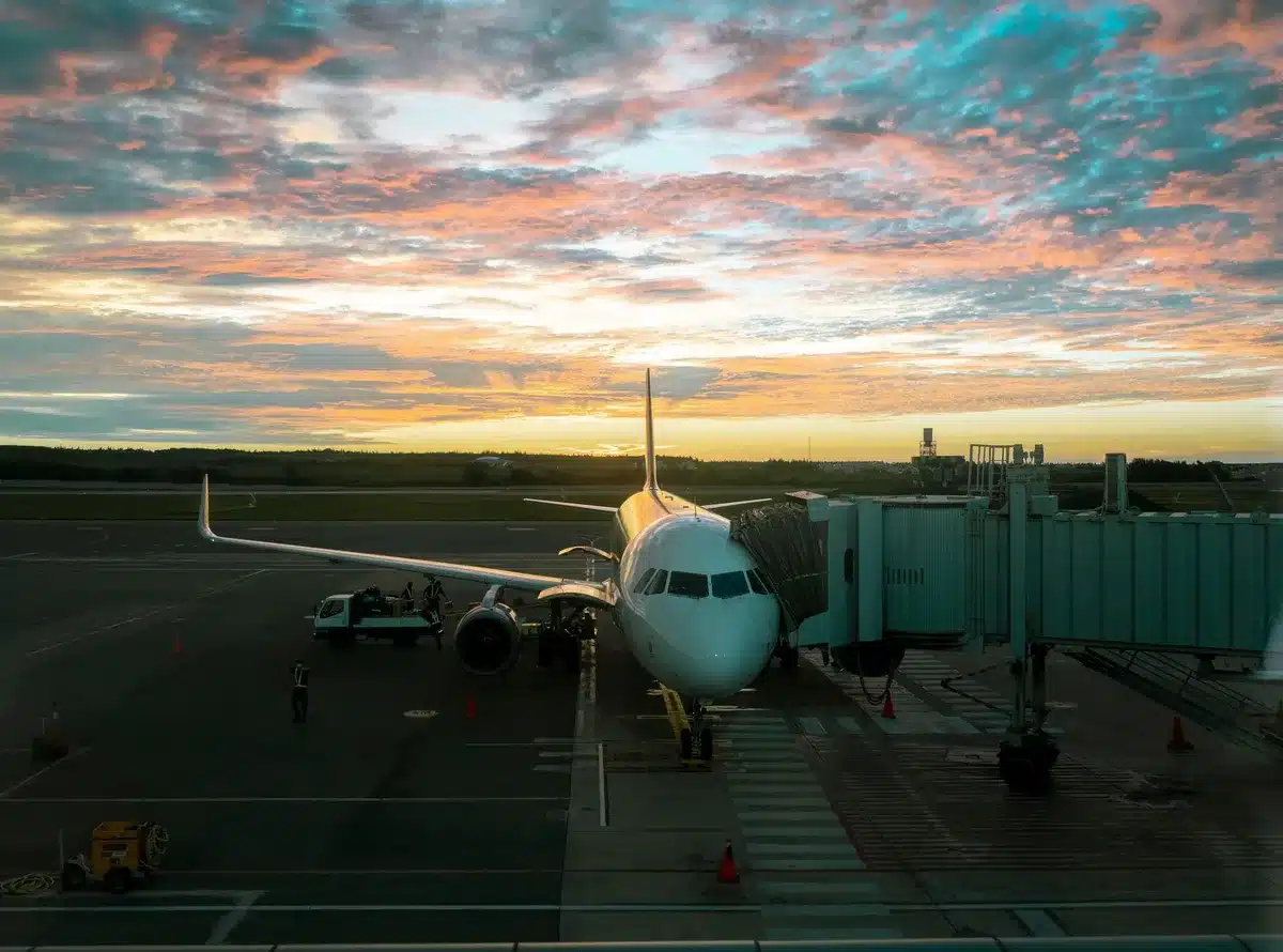 Airbus A220-300 aircraft parked at a gate with boarding bridge attached, showing the modern narrow-body jet design