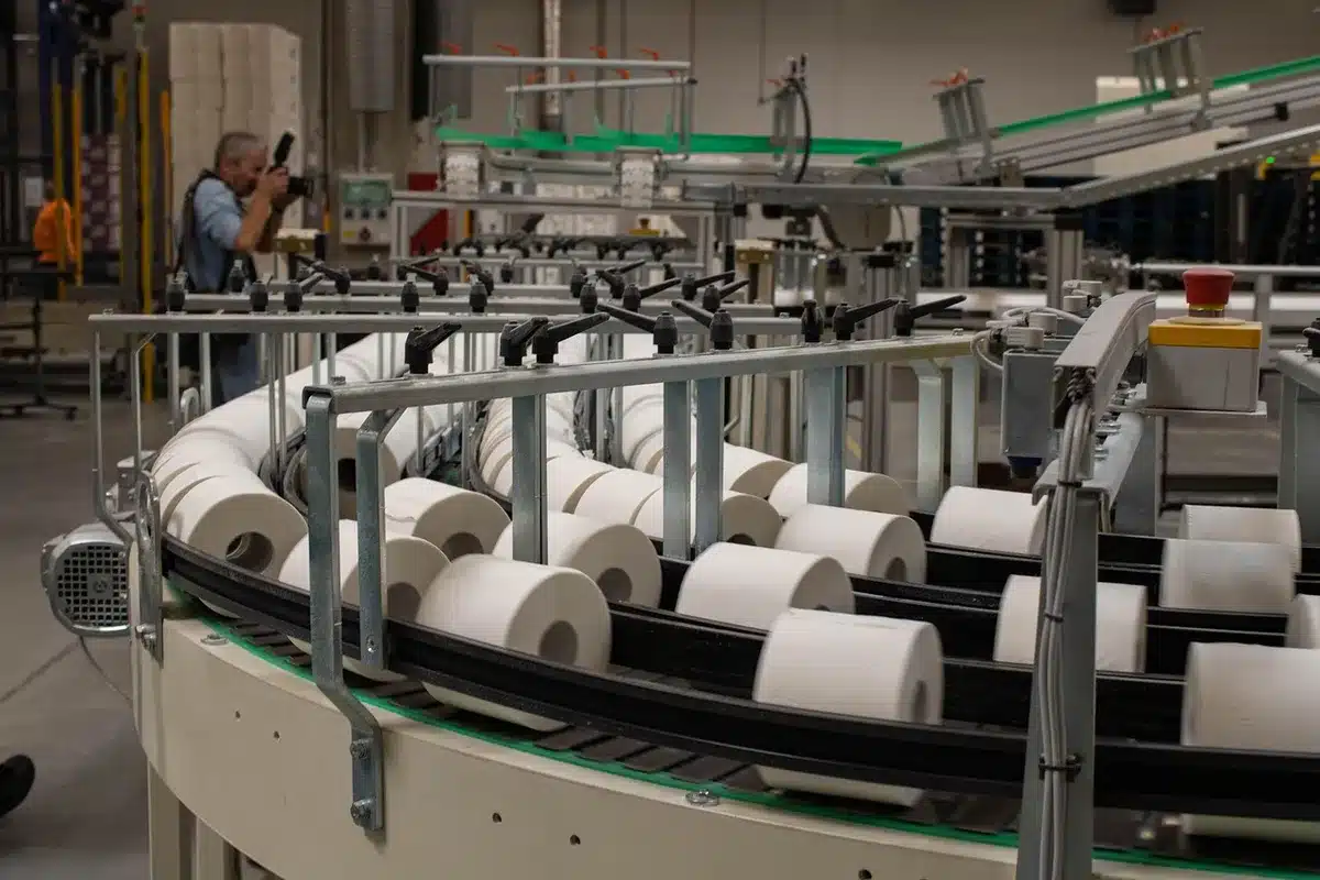 Interior of a modern meat processing facility with stainless steel equipment and conveyor systems, empty and ready for production. Industrial lighting and clean surfaces visible.