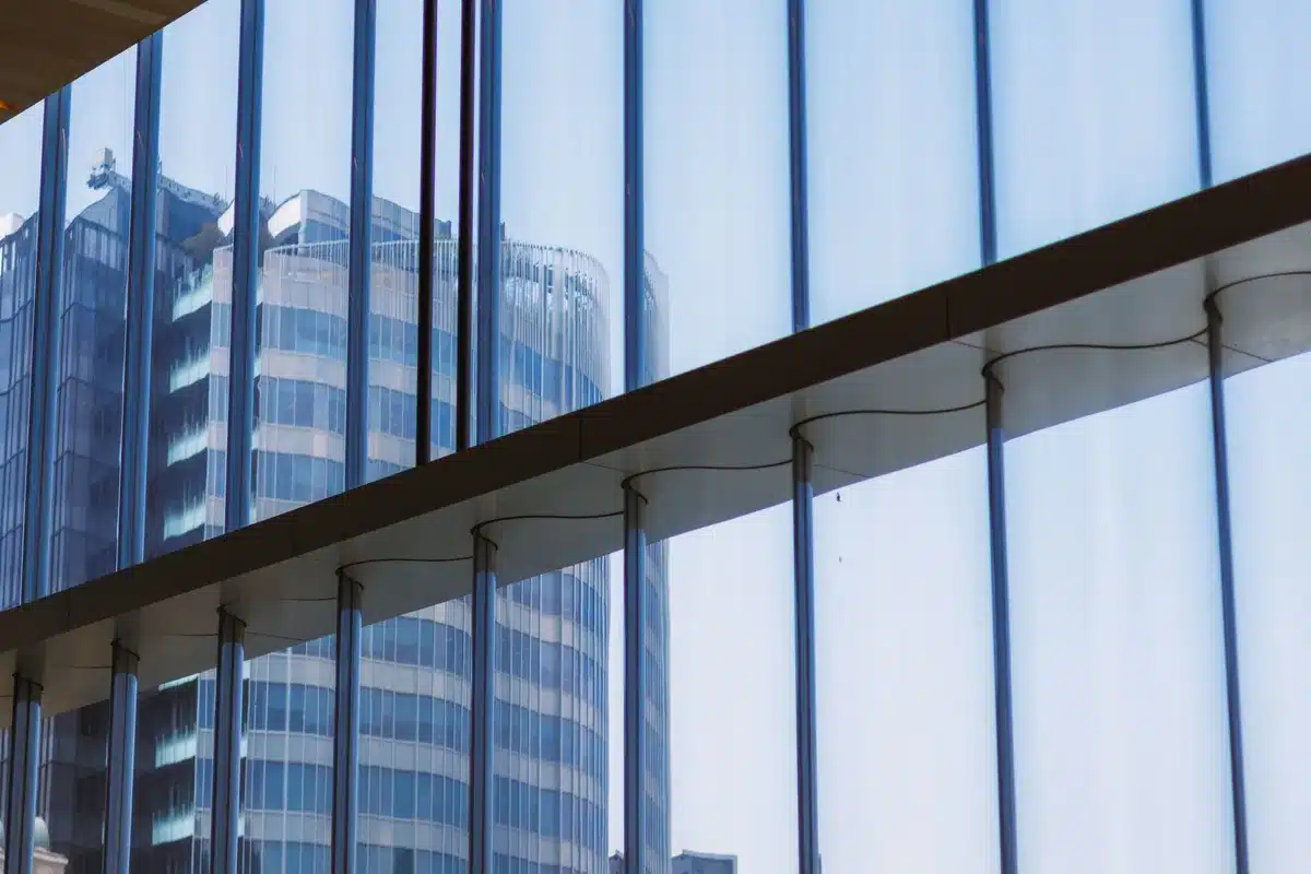 A sprawling corporate campus at dusk with lights coming on in office windows, a few silhouetted figures walking across a plaza, the Berkshire Hathaway sign illuminated&mdash;continuity