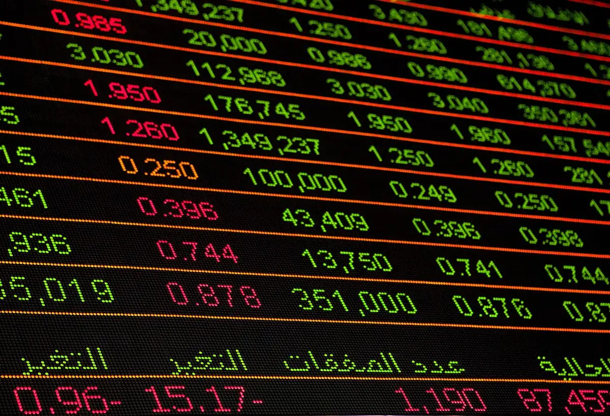 Anonymous investor at a glowing trading terminal, market data streaming across multiple screens, hands poised over keyboard, cool blue light reflecting off focused face silhouette
