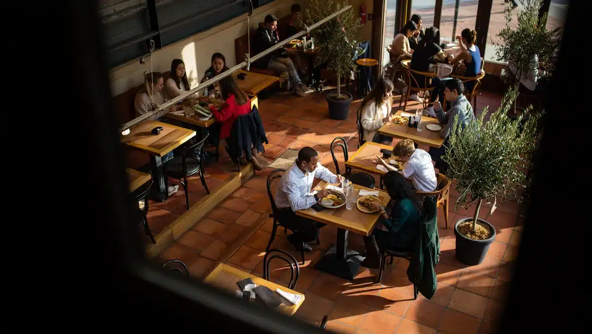 Bustling CAVA restaurant interior with customers at tables, Mediterranean-inspired decor, natural daylight from windows | busy casual dining restaurant interior