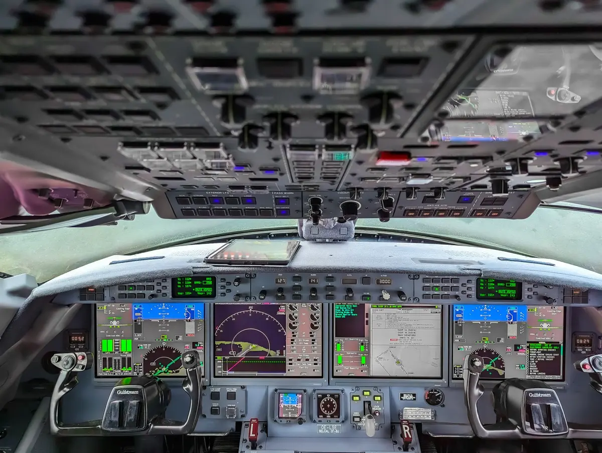 Close-up of an aircraft's instrument panel showing engine gauges and warning lights, with a pilot's hand visible near the controls.