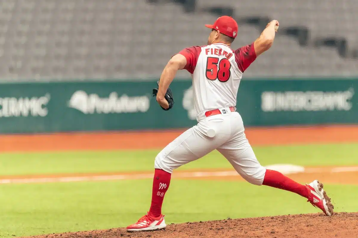 Relief pitcher in mid-delivery on the mound, stadium lights casting shadows, intense focus captured mid-pitch, arm extended at release point