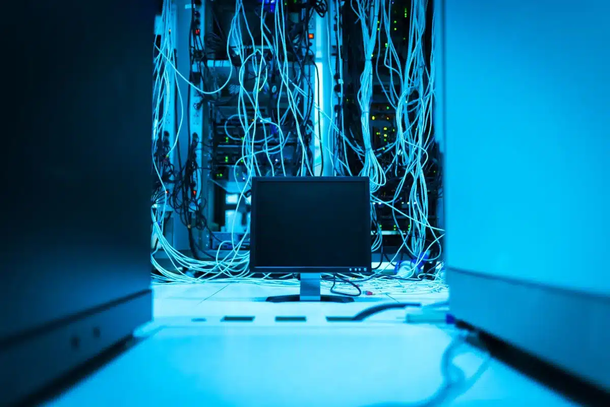 Networking equipment and server infrastructure in dimly lit data center, cables and lights blurred in background