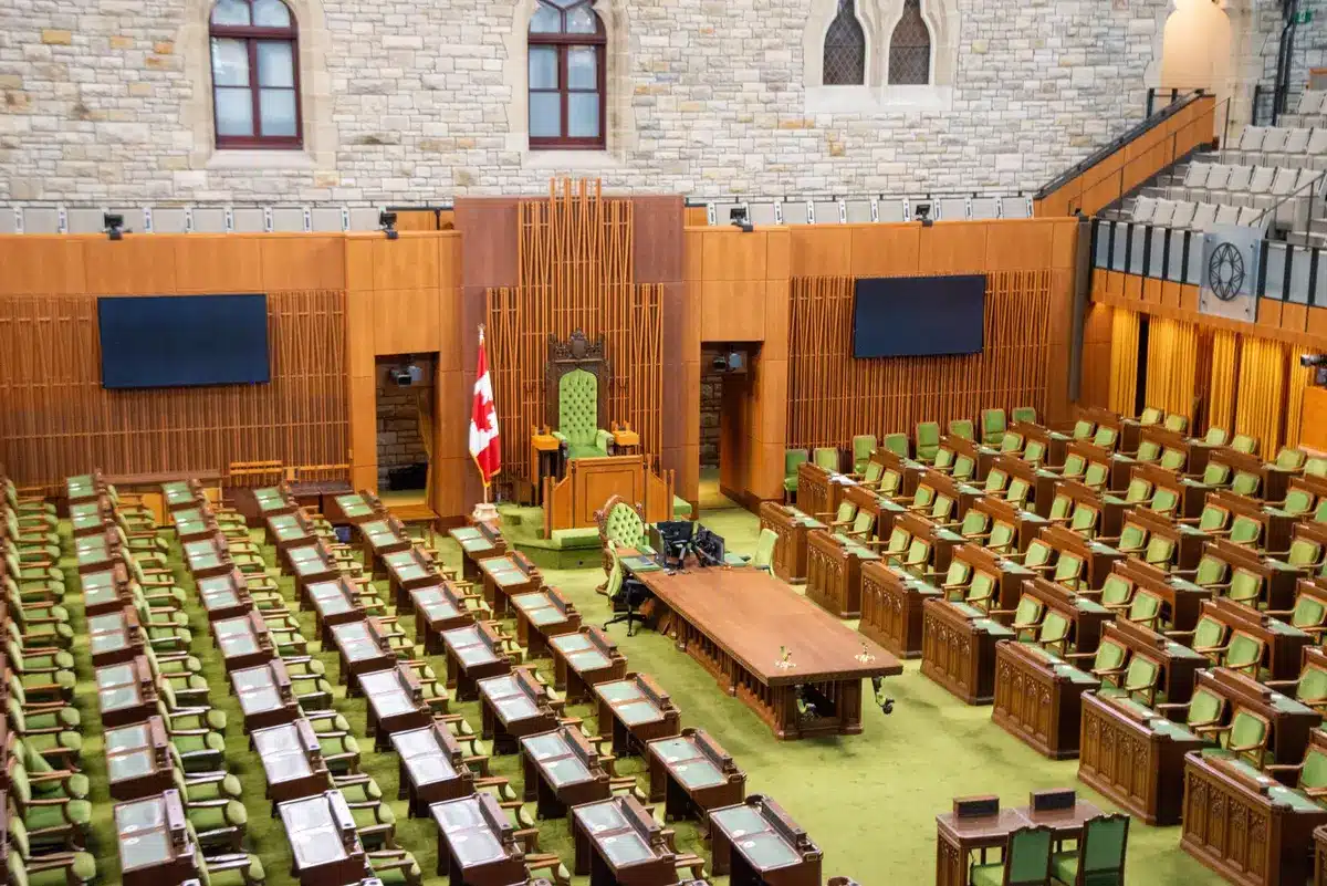 Senate chamber floor with empty desks, a single gavel catching light on the presiding officer's bench, an American flag in soft focus behind, anticipation before a pivotal vote