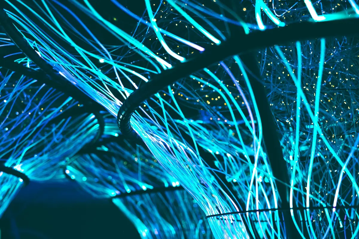 Data center server racks illuminated with blue and green lights, optical cables connecting hardware