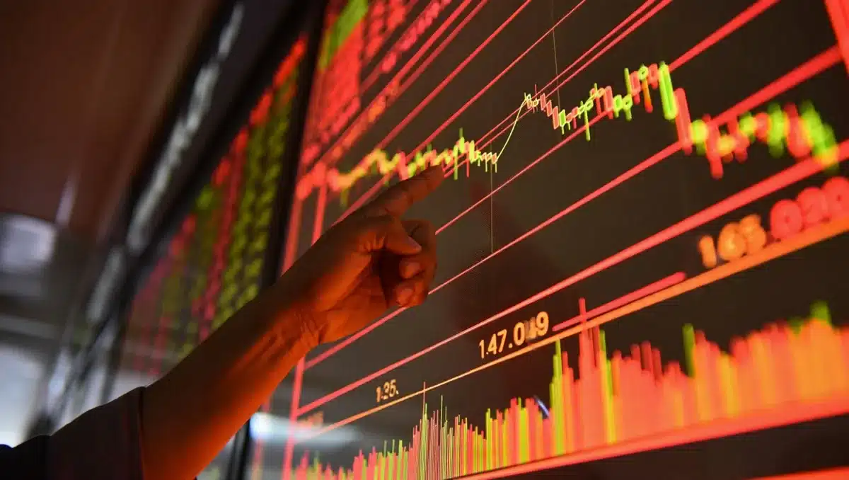A stock market ticker display showing red and green price movements, candlestick charts with declining trend lines, a hand pointing at the screen, warm and cool lighting contrasts | stock market chart decline