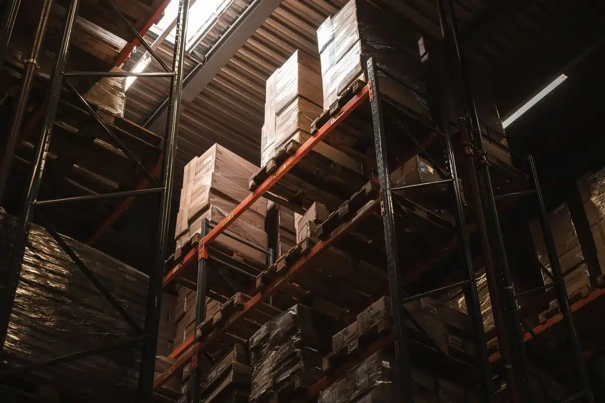 Warehouse interior with rows of merchandise and shopping carts, customers browsing bulk items under fluorescent lighting.