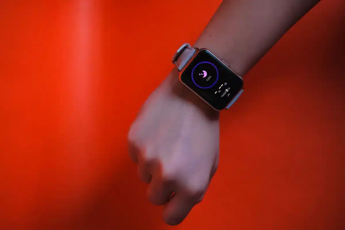 A wearable smartwatch displaying heart rate and health metrics next to a blood pressure monitor cuff on a table