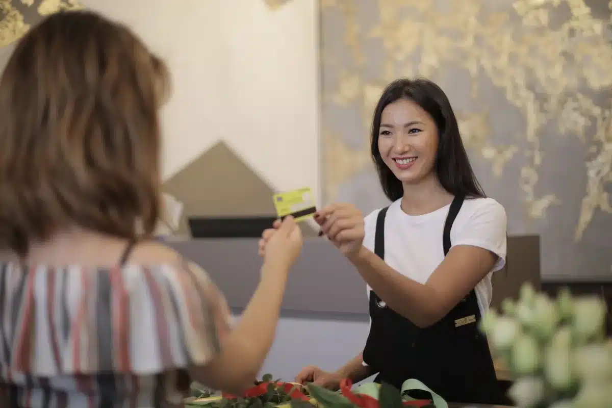 A credit card held in hand against a blurred shopping environment, soft retail lighting in background
