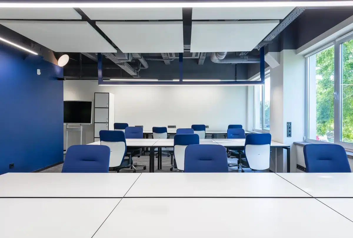 A modern office boardroom with floor-to-ceiling windows overlooking a cityscape, empty conference table with chairs, soft natural light streaming in, creating a sense of anticipation and professional dialogue
